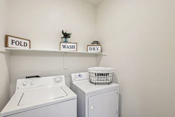 A laundry room with a washer and dryer and a laundry basket on top of the dryer